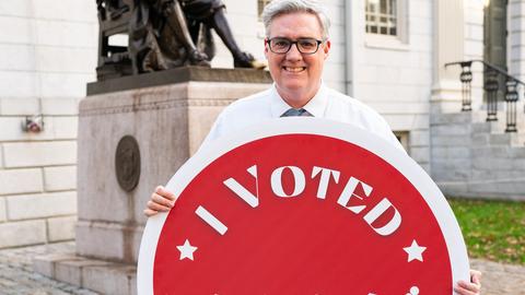 A man holding an "I Voted" sign. 